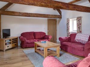 a living room with two red couches and a table at Priory Barn in Frocester