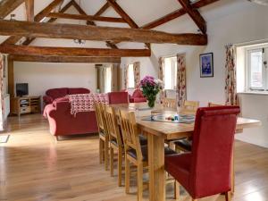a dining room and living room with a wooden table and chairs at Priory Barn in Frocester