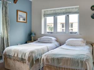 two beds in a room with a window at Priory Barn in Frocester