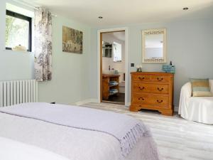 a bedroom with a bed and a dresser and a mirror at Ivy Cottage in Westfield