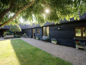 a house with a patio with benches and flowers at Ivy Cottage in Westfield