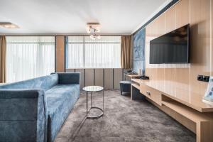 a living room with a blue couch and a tv at Гранд Хотел Княз Павел in Pavel Banya