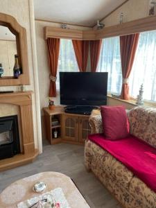 sala de estar con sofá y TV de pantalla plana en Mobilhome en Noyelles-sur-Mer