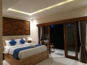 a bedroom with a large bed and a large window at Cahaya Guest House in Ubud