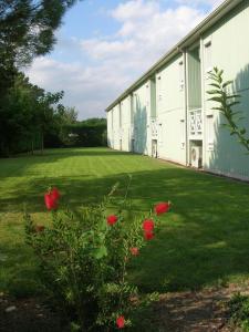 a large white building with red flowers in the yard at Fasthotel Avignon Nord Le Pontet in Le Pontet