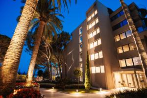 a hotel with palm trees in front of a building at Palmon Bay Hotel & Spa in Herceg-Novi