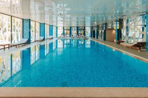 a large swimming pool with blue water in a building at Palmon Bay Hotel & Spa in Herceg-Novi
