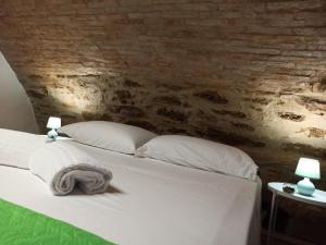 uma cama com almofadas brancas e uma parede de tijolos em Matalena em Pomarico