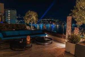 a rooftop patio with a couch and a view of the water at night at Palmon Bay Hotel & Spa in Herceg-Novi