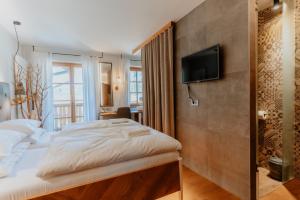 a bedroom with a bed and a tv on a wall at Hotel Plesnik Logarska Dolina in Solčava