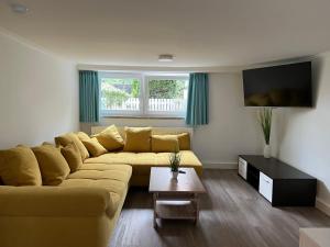 uma sala de estar com um sofá amarelo e uma televisão em Gästehaus Blauth em Cuxhaven