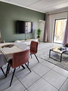 a living room with a table and chairs and a tv at Loadshedding Equipped 2-Bed Apartment in Waterfall, Waterfall City in Midrand