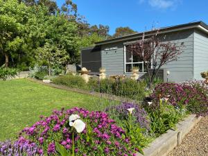 a garden with flowers in front of a house at Cozy Cottage Victor Harbor in Hindmarsh Valley