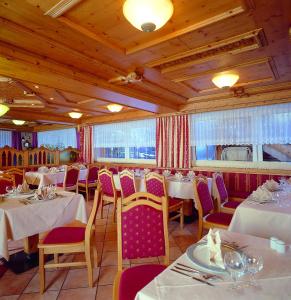 a restaurant with white tables and chairs and wooden ceilings at Piz Alpin B&B in Colfosco