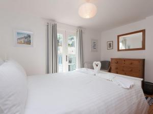 a white bedroom with a large white bed and a window at Kitcat Cottage in Dartmouth