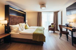 a hotel room with a large bed and a desk at Genusshotel Goldene Rose in Silandro