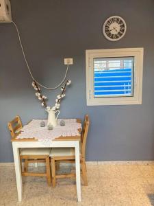 a table and chairs with a vase and a clock on the wall at יחידת נופש מדהימה ומעוצבת לנופש מושלם בערד in Arad