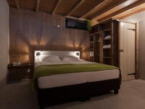een slaapkamer met een groot bed en een houten muur bij Norgerbrink in Norg