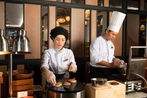two chefs standing in a kitchen preparing food at Fleur de Lys Hotel Quy Nhon in Quy Nhon +86 photos