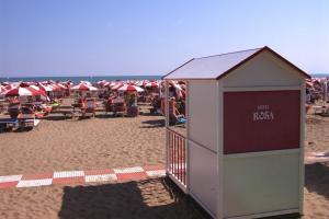 a building on a beach with red and white umbrellas at Giovanna Rooms in Caorle