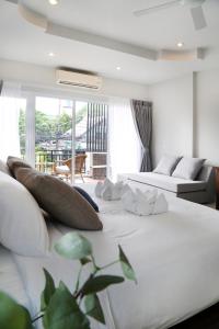 a large white bed with pillows on top of it at The Langstan Suites in Nai Harn Beach