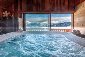 a jacuzzi tub with a view of the mountains at Chalet Hôtel Les Blancs in Pra-Loup