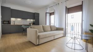 a living room with a couch and a kitchen at Apartamentos Boutique Puerta de Reyes in Toledo