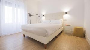 Un dormitorio con una gran cama blanca y una ventana en Apartamentos Boutique Puerta de Reyes, en Toledo