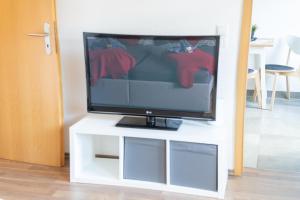 een flatscreen-tv zittend op een witte tv stand bij FULL HOUSE Studios - Apartment French Touch in Zwickau