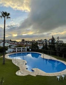 une grande piscine bleue avec un palmier dans l'établissement Pueblo Jardín charming Andalusian complex, à Benalmádena