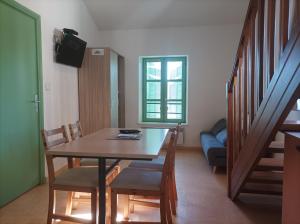 a dining room with a table and chairs and a couch at Gîte L'Olivier in Le Val