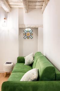 a green couch in a living room with a painting at Casa Kawaii Midori in Cagliari