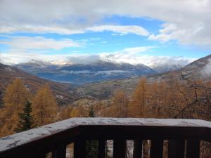 uma vista para as montanhas cobertas de neve a partir de um banco em Les écureuils du Méale em Les Orres