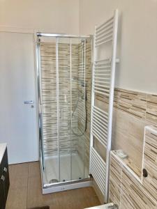 una ducha con puerta de cristal en un baño en Palazzo Proietti 4, en Biella