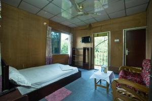 a bedroom with a bed and a chair and a window at Fanush Resort in Bāndarban