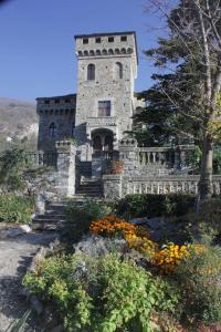 un viejo edificio de piedra con flores delante en Romantic Italian Castle at the foot of the Alps en Settimo Vittone