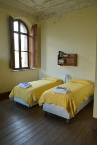 2 camas en un dormitorio con ventana en Romantic Italian Castle at the foot of the Alps en Settimo Vittone