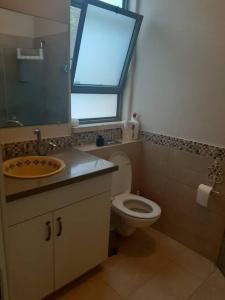 uma casa de banho com um WC, um lavatório e uma janela em A Spot on the Hill em Umm el Shuf
