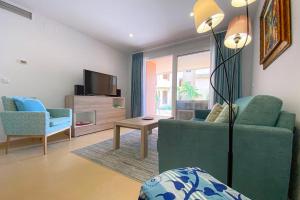 a living room with a green couch and a tv at Superb luxurious groundfloor 1 bedroom app on Mar Menor golf resort in Torre-Pacheco
