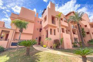un edificio con palmeras delante en Superb luxurious groundfloor 1 bedroom app on Mar Menor golf resort en Torre-Pacheco