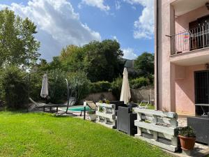 un patio con bancos y sombrillas y una piscina en La casa di Silvia, en Cantalupo in Sabina