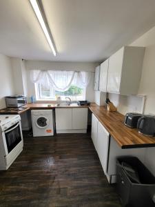 a small kitchen with white cabinets and a sink at Emerald House in Luton