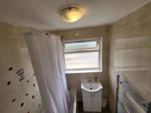 a bathroom with a white shower curtain and a sink at Emerald House in Luton