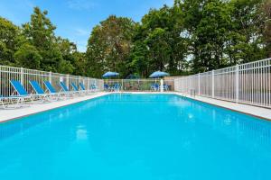 a swimming pool with blue chairs and a fence at Travelodge by Wyndham Cape Cod Area in West Dennis