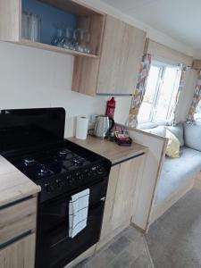 a kitchen with a stove and a couch in a room at New 2 bed holiday home with decking in Rockley Park Dorset near the sea in Lytchett Minster