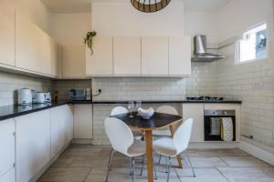a kitchen with a wooden table and white chairs at Luxury, very central and spacious house in Brighton & Hove