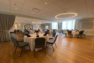 un salón de banquetes con mesas y sillas blancas en Ramada Plaza by Wyndham Montreal, en Montreal