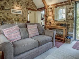 a living room with a couch and a stone wall at Primrose Cottage - HW7100 in Amroth