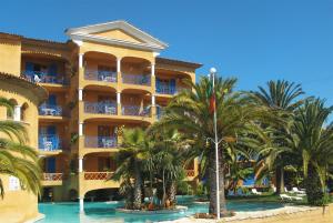 un grand bâtiment jaune avec des palmiers devant lui dans l'établissement Hotel Quinta Da Lagoa, à Praia de Mira