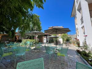 een patio met stoelen, tafels en parasols bij Hotel TREVA in Shkodër